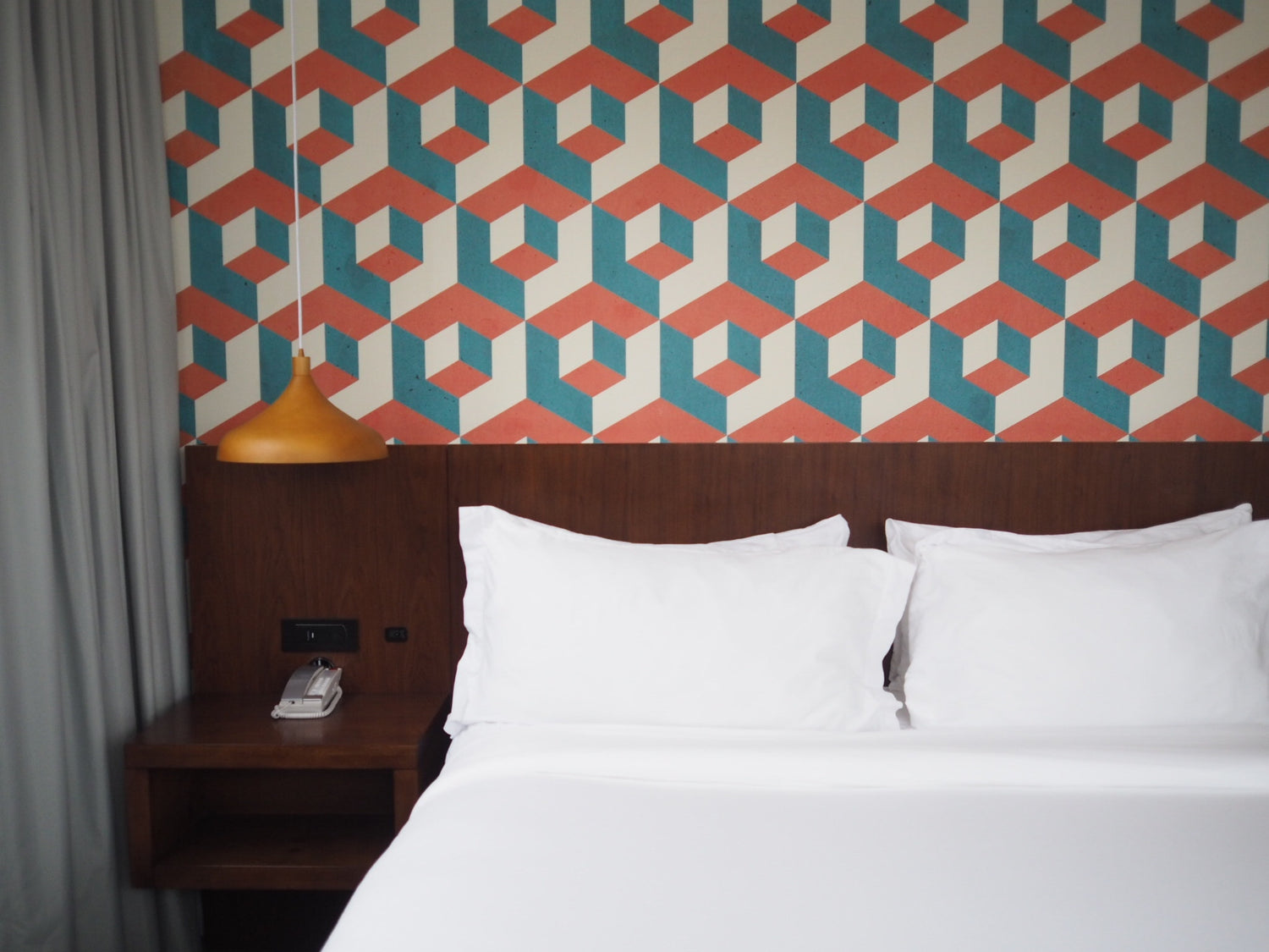 a bed with orange and teal hexagon wallpaper